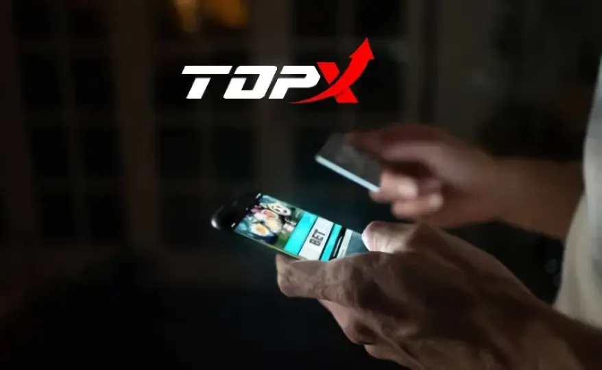 Imagem de marca da TopX: mãos segurando um celular numa sala escura